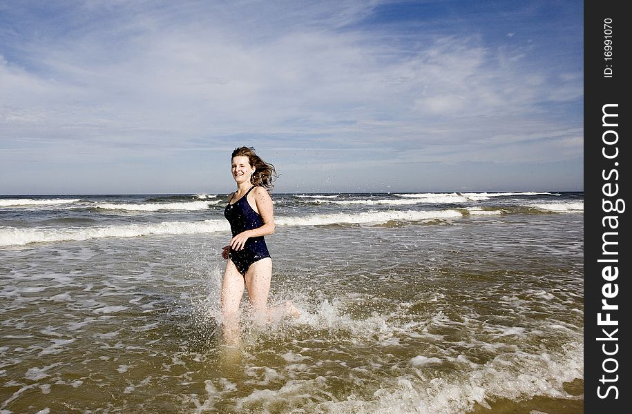 Young woman running through the wave