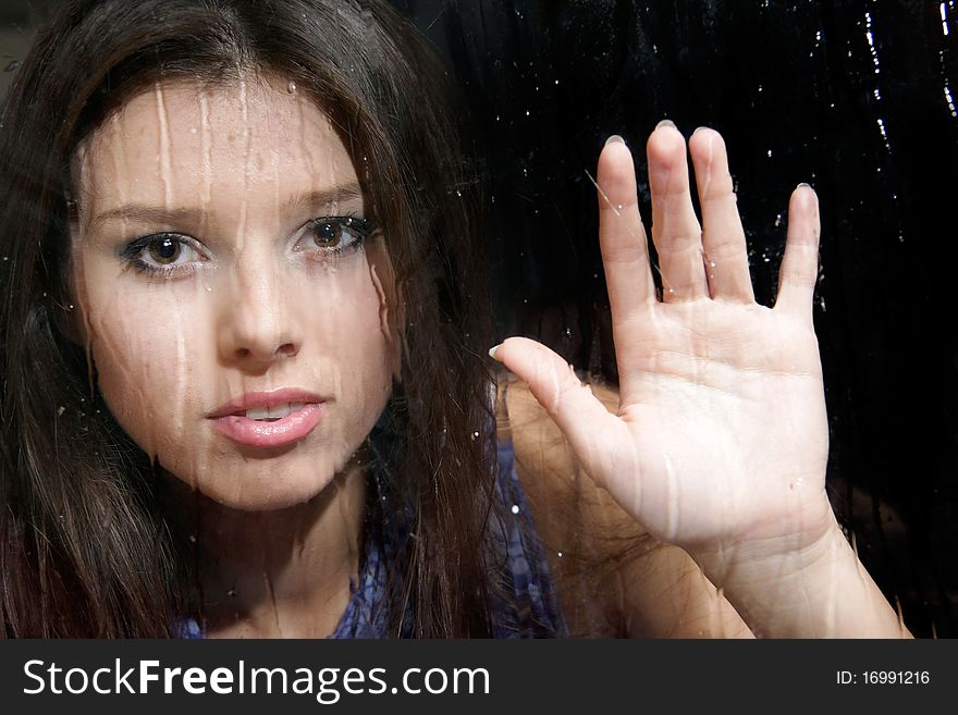 Young girl behind wet window