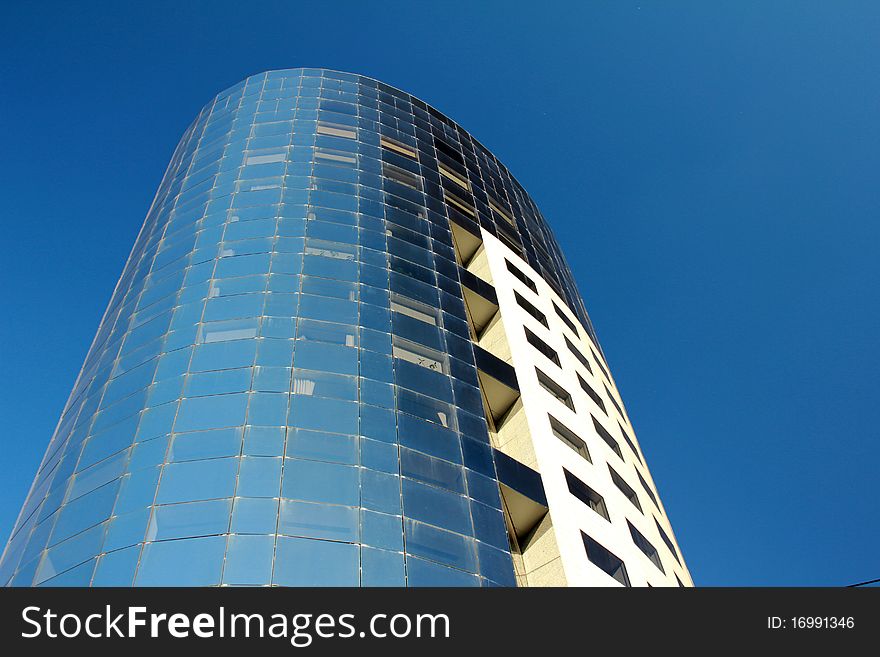 Image of blue glass and steel skyscraper with blue sky in the background. Image of blue glass and steel skyscraper with blue sky in the background