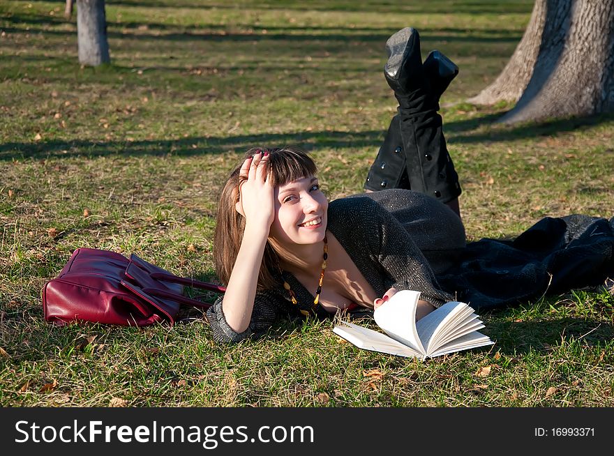 Girl reading while lying in a park on the grass