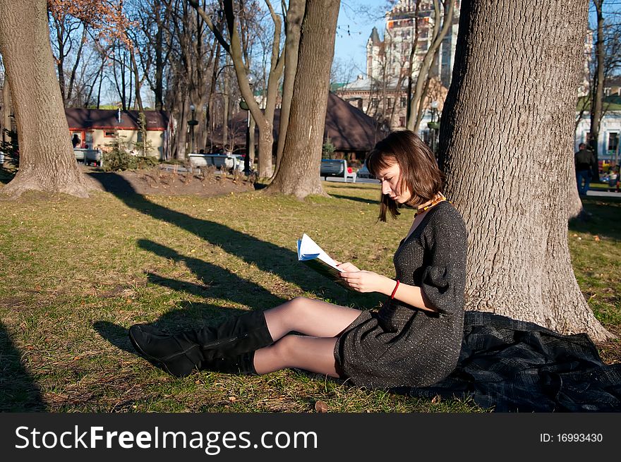 Girl reading while sitting in a park on the grass
