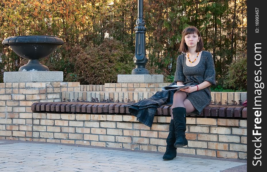 Girl reading a magazine on a park bench. Girl reading a magazine on a park bench