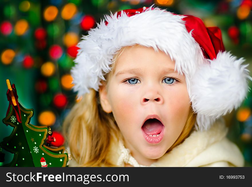 Surprised small girl in Santa's hat looking for a Christmas gifts. Surprised small girl in Santa's hat looking for a Christmas gifts