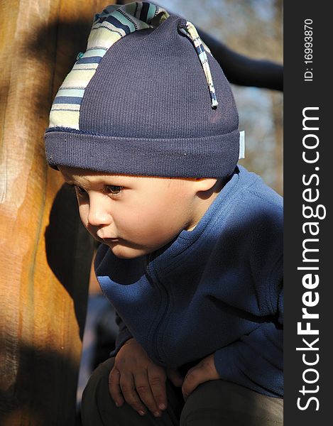 Young boy squatting on a playground wooden construction. Young boy squatting on a playground wooden construction