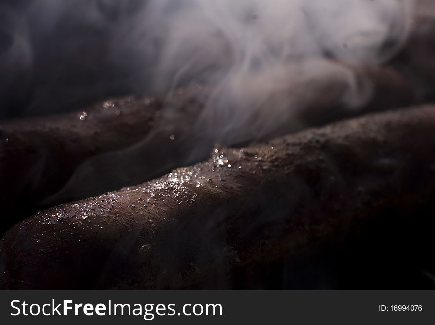 Cooking sausage on grill with smoke , close-up picture