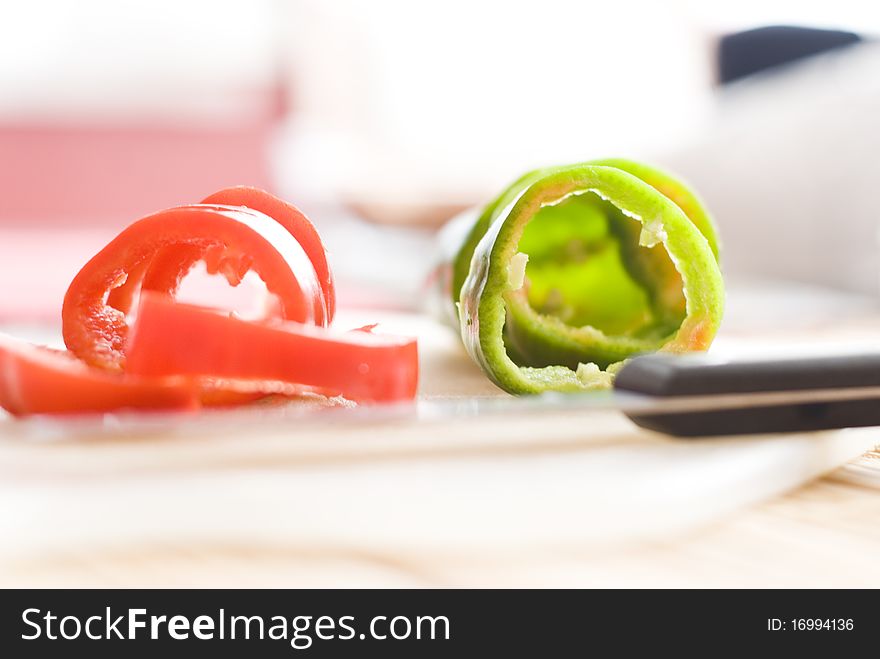 Cuted pieces of red and green pepper on board with knife. Cuted pieces of red and green pepper on board with knife