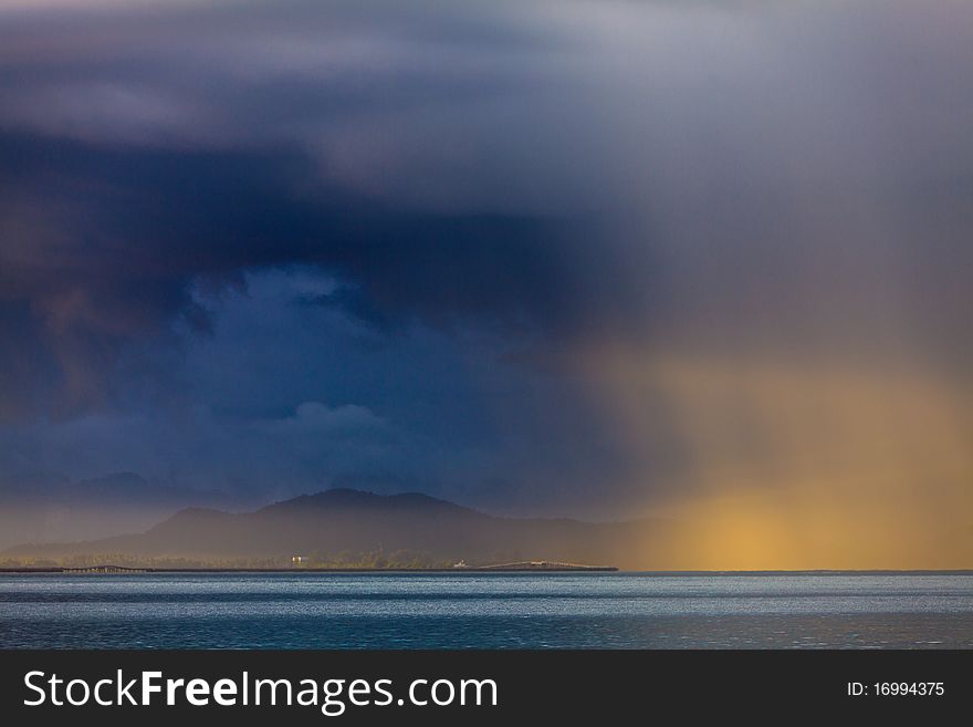 Thunder storm with rain lit by the sun at a lake