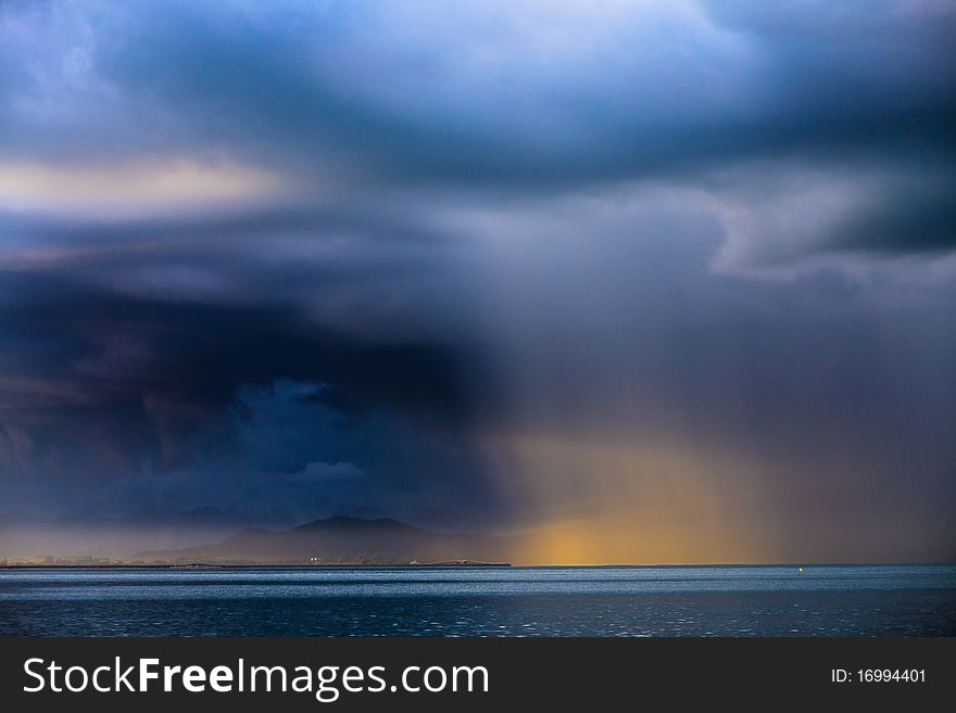 Thunder storm with rain lit by the sun at a lake