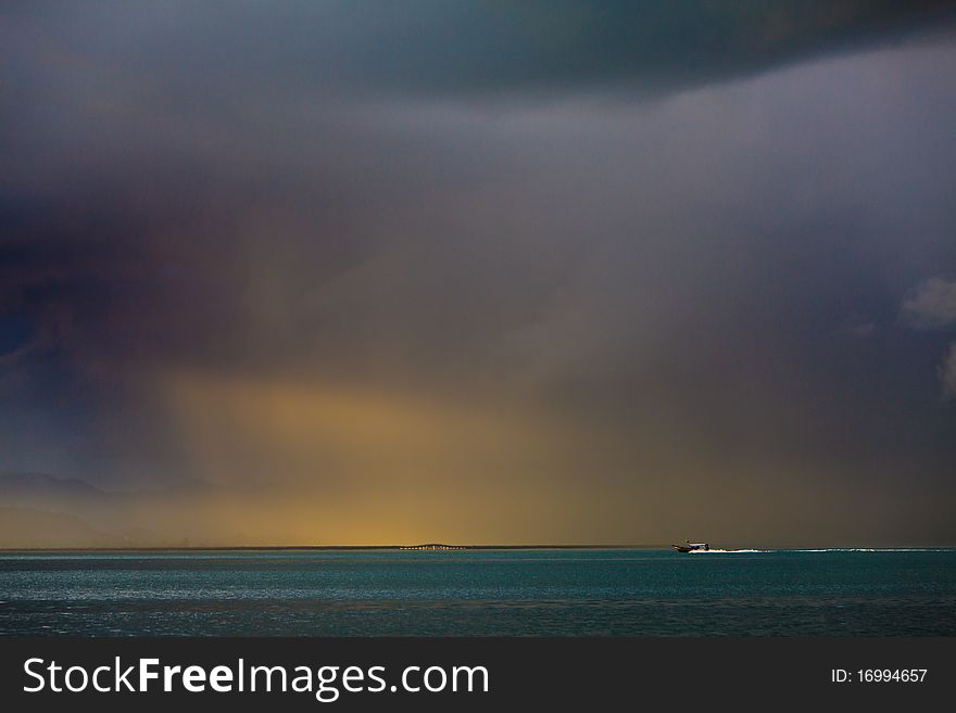 Thunder storm with rain lit by the sun at a lake