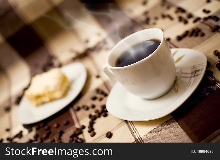 Very hot coffee in cup and cake on table, cake in blurred background. Very hot coffee in cup and cake on table, cake in blurred background