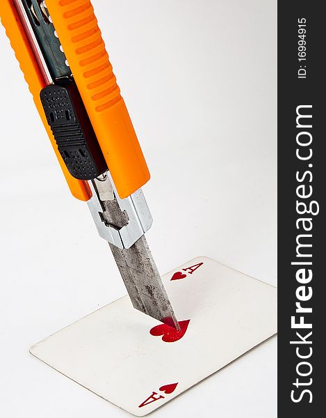 Utility knife pointing at a playing card