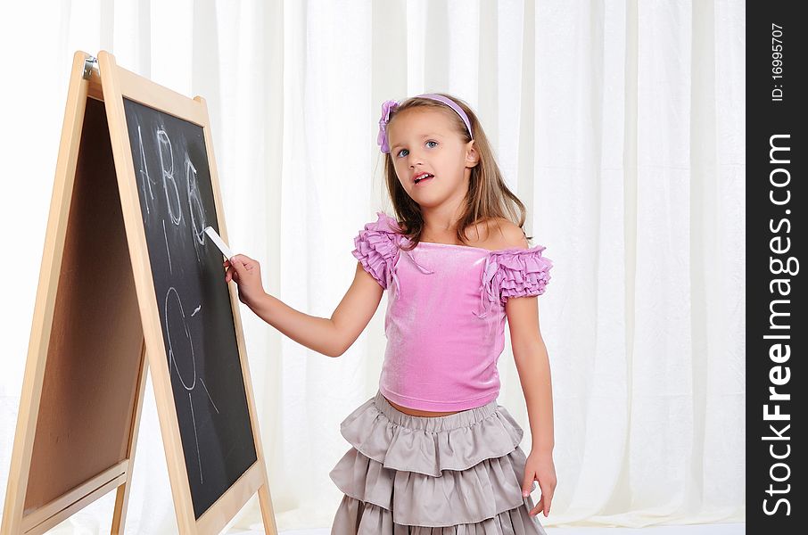 A little girl wrote in chalk on the graphite board. Receive their education.