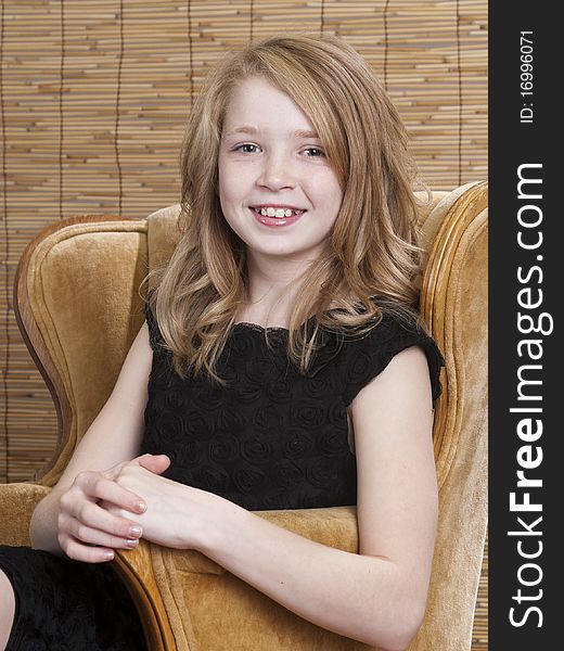 Young preteen girl looking off to the side while sitting in a chair with circle background. Young preteen girl looking off to the side while sitting in a chair with circle background