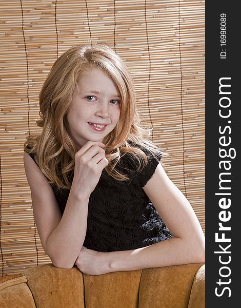 Young preteen girl looking off to the side while sitting in a chair with circle background. Young preteen girl looking off to the side while sitting in a chair with circle background