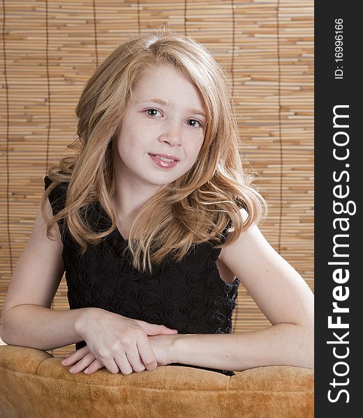 Young preteen girl looking off to the side while sitting in a chair with circle background. Young preteen girl looking off to the side while sitting in a chair with circle background