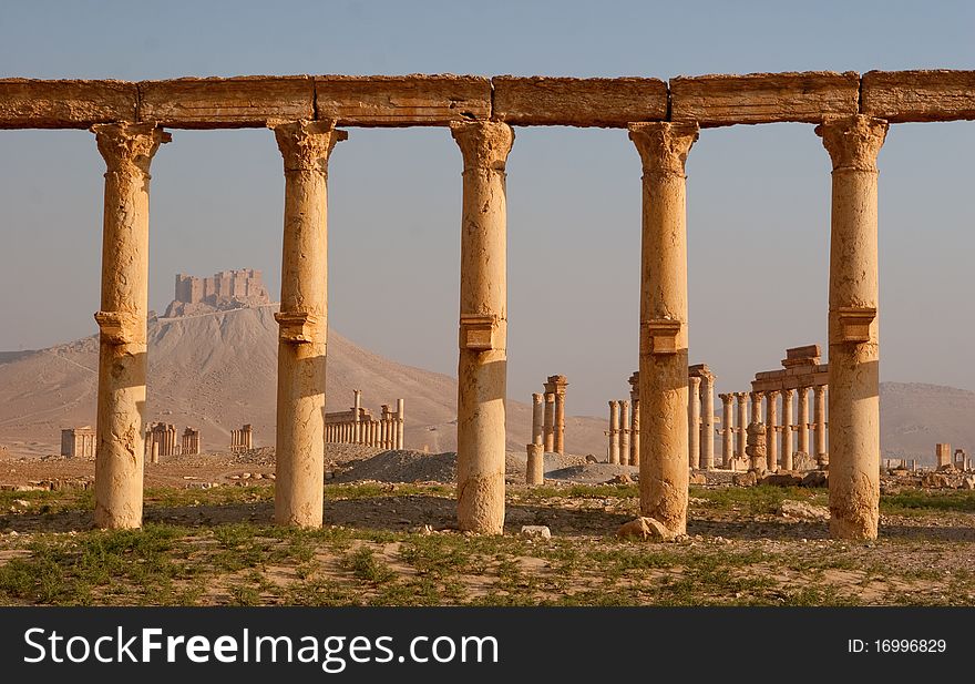 Columns in ancient Palmyra in Syrian desert with islamic fort. Columns in ancient Palmyra in Syrian desert with islamic fort.