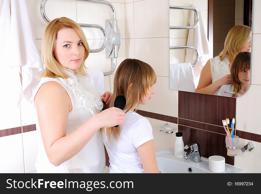 A young girl and her mother take care of the hair in his bathroom
