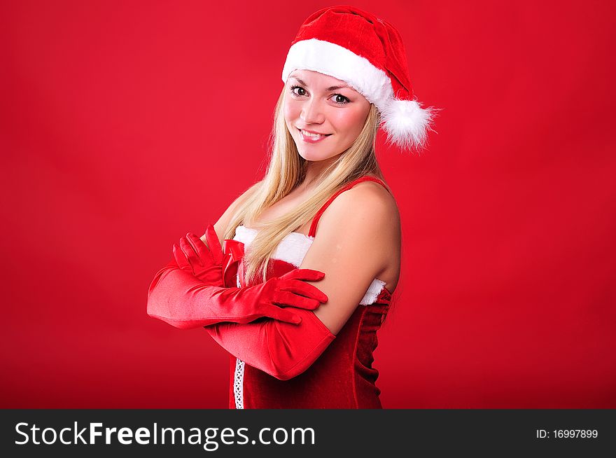 Portrait of a young girl dressed as Santa Claus on a red background. Happy New Year and Merry Christmas!