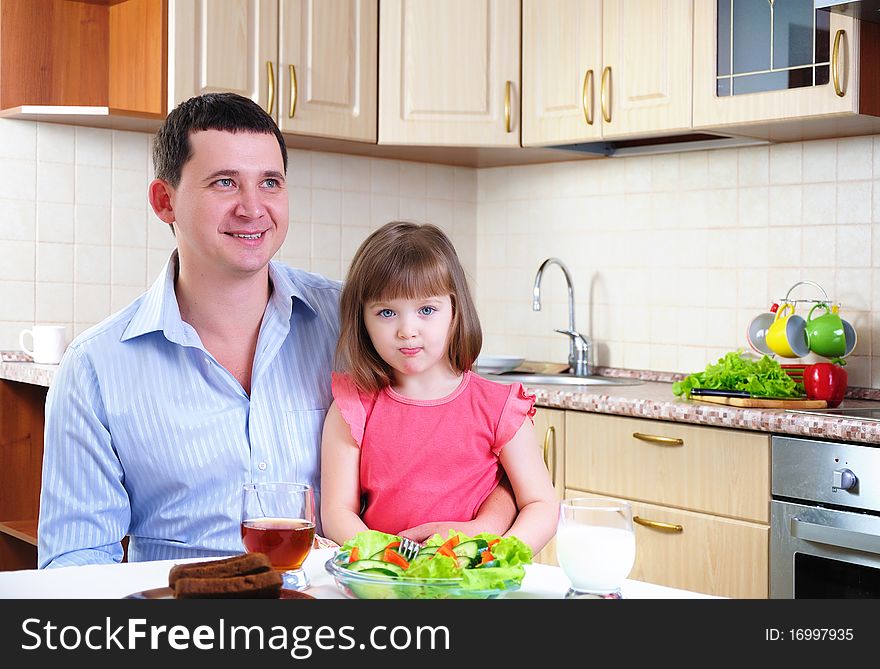 Father and his young daughter eat breakfast together in his kitchen.