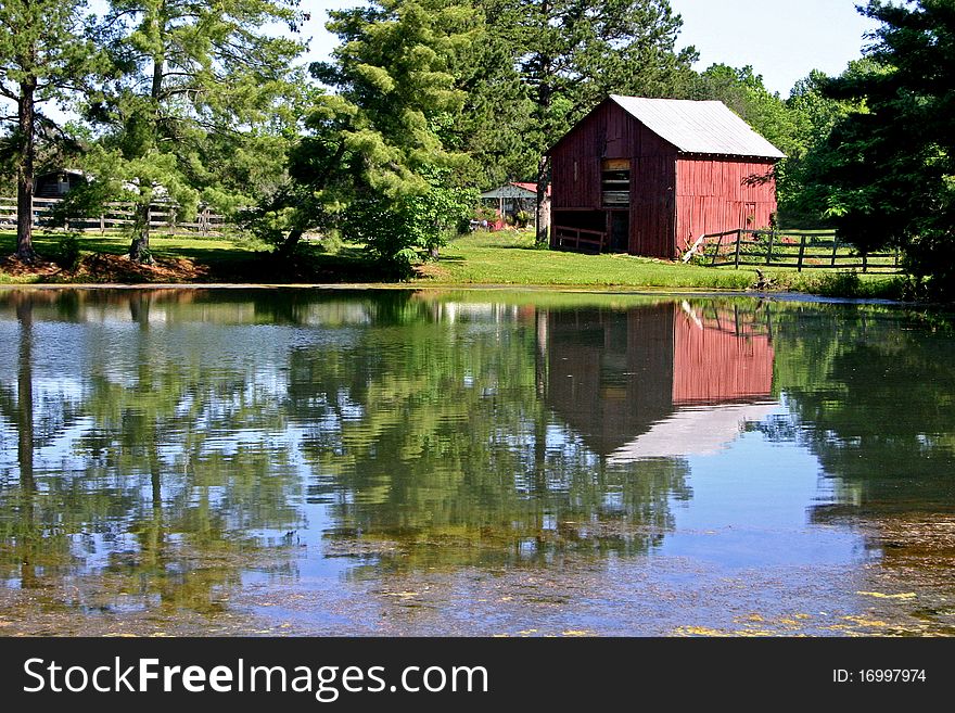 A red barn reflected on the surface of a small pond. A red barn reflected on the surface of a small pond