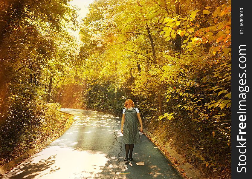 The pregnant woman walks on autumn park in sun rays