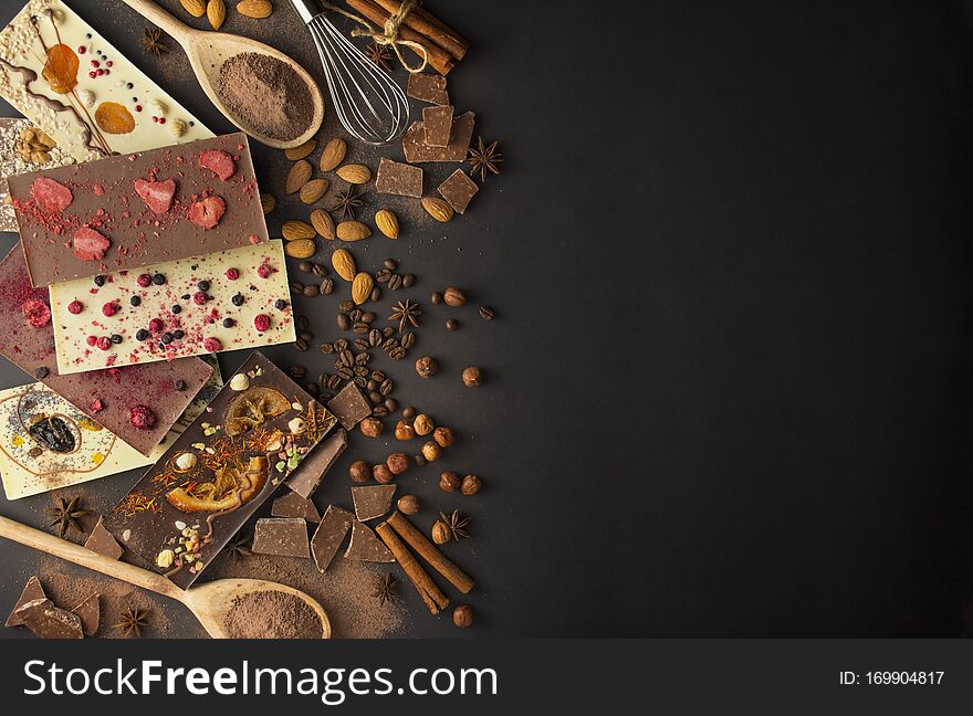 Handmade chocolate with berries, nuts, dried fruits on a dark background. Black and white chocolate. Chocolate bar. Chocolate