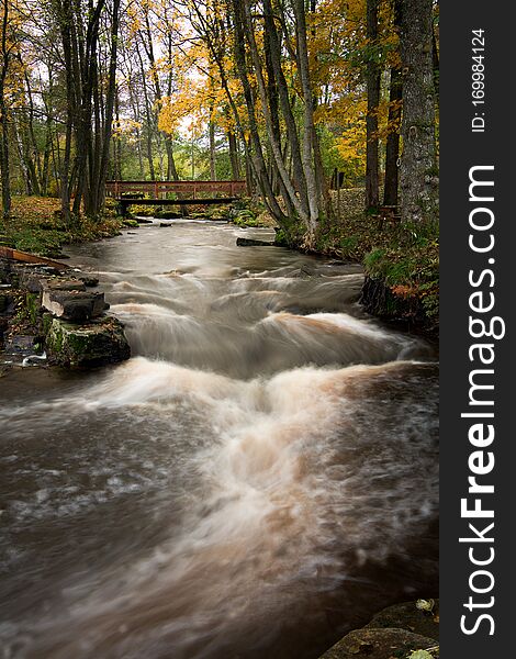 A bridge over the river in autumn colors. Streaming water. A bridge over the river in autumn colors. Streaming water.