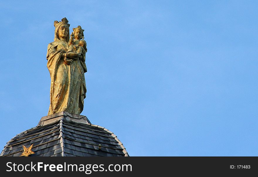 A golden statue of the virgin Mary holding a young Jesus in her arms