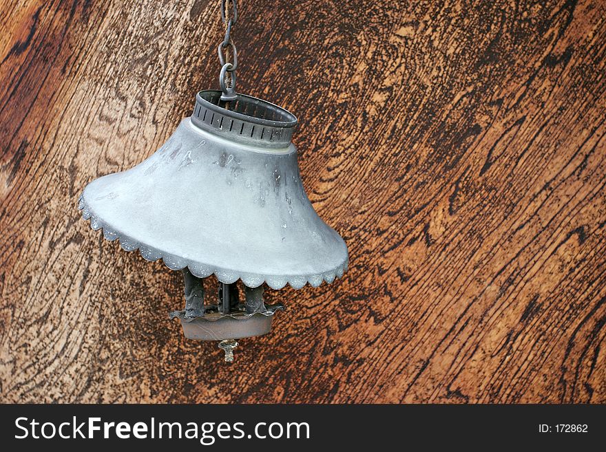 An old, broken electric lamp, hangs on a chain with its cooked shade. An old, broken electric lamp, hangs on a chain with its cooked shade.
