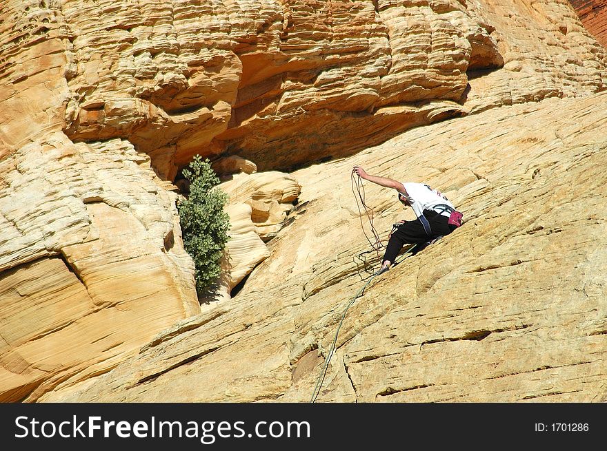 A guy checking his ropes while climbing a mountain. A guy checking his ropes while climbing a mountain.