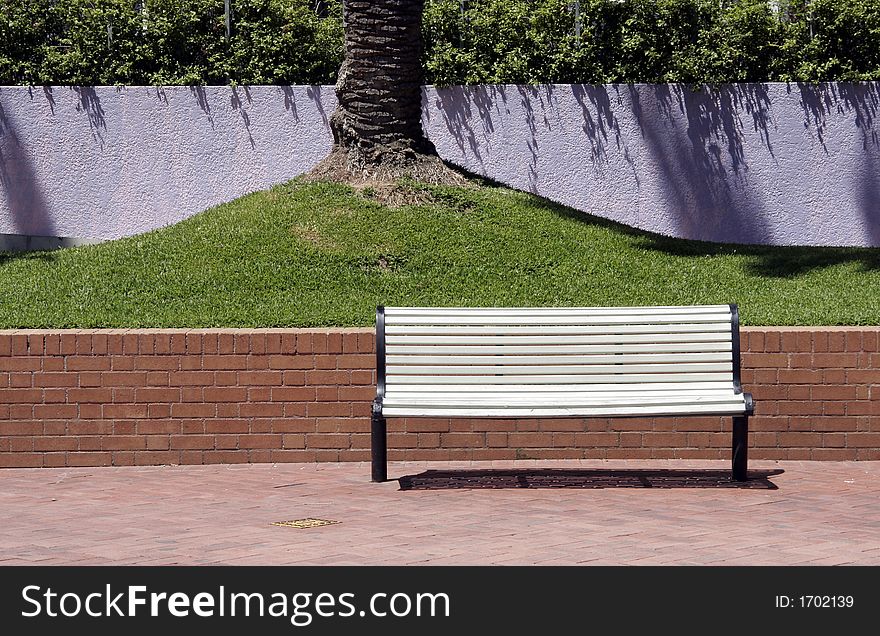 Empty White Bench In Front Of Green Grass And A Purple Wall
