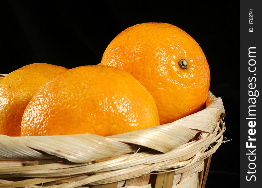 Clementines imported from Spain in a basket on a black background. These are also knows as Satsumas and are grown in southern Louisiana.