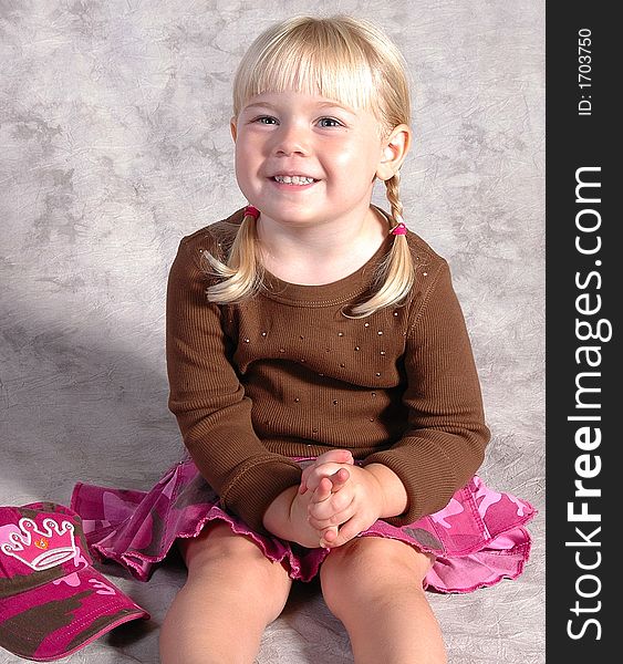 A cute little girl posing on a gray background. A cute little girl posing on a gray background.