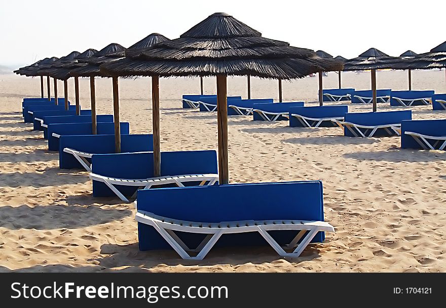 Sunshades and chaises long on an empty beach