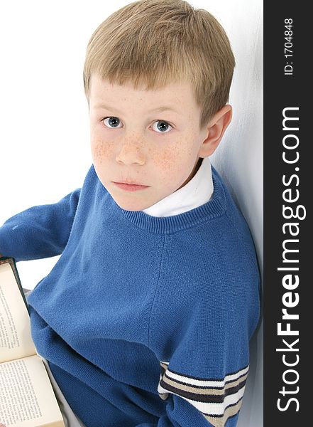 Adorable 8 year old boy leaning against wall with book. Blue eyes, blond hair. Adorable 8 year old boy leaning against wall with book. Blue eyes, blond hair.