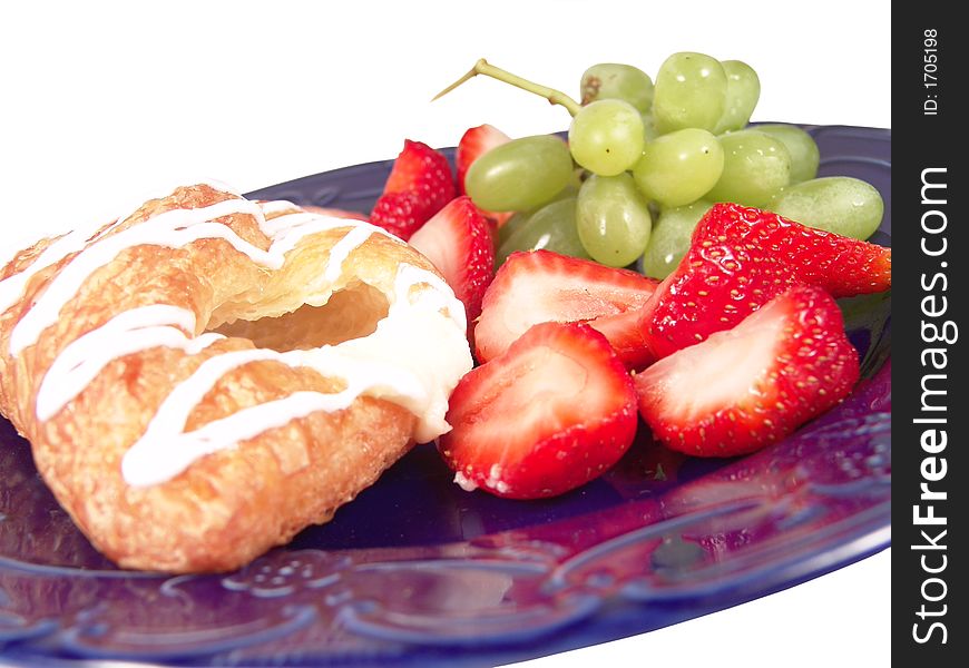 Pastry, grapes and strawberry on a blue plate