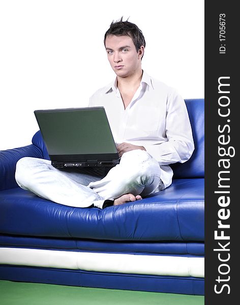 Young man comfortably sitting in a sofa using a laptop. Young man comfortably sitting in a sofa using a laptop