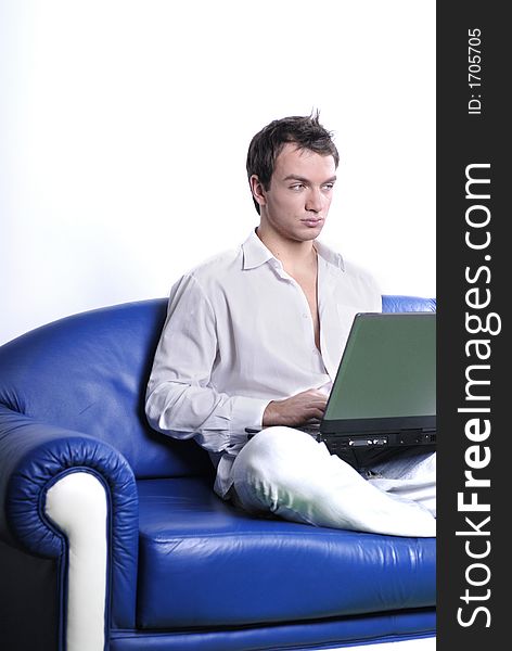 Young man comfortably sitting in a sofa using a laptop. Young man comfortably sitting in a sofa using a laptop