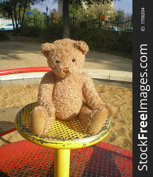 Teddy bear on the merry-go-round on the payground