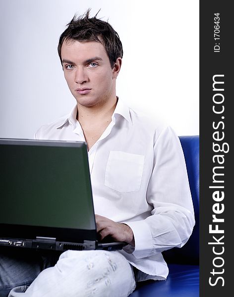 Young man comfortably sitting in a sofa using a laptop. Young man comfortably sitting in a sofa using a laptop