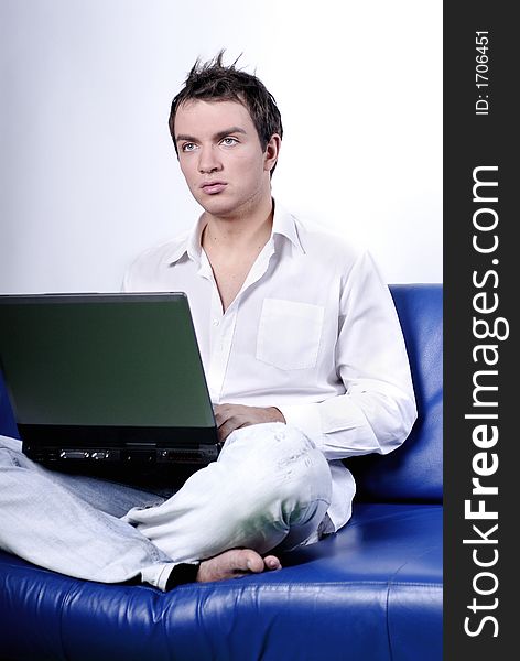 Young man comfortably sitting in a sofa using a laptop. Young man comfortably sitting in a sofa using a laptop