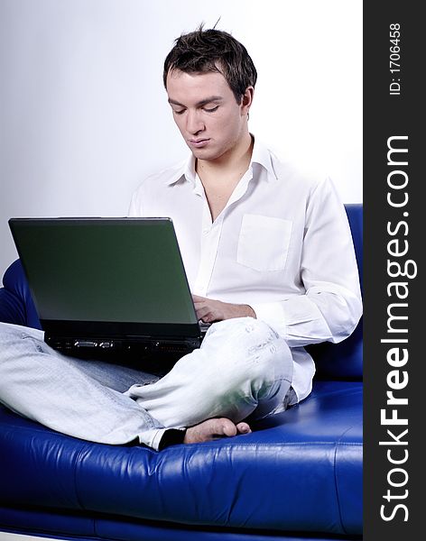 Young man comfortably sitting in a sofa using a laptop. Young man comfortably sitting in a sofa using a laptop