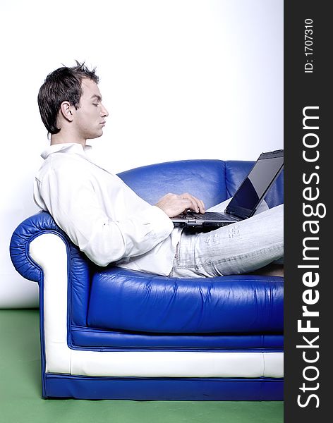 Young man comfortably sitting in a sofa using a laptop. Young man comfortably sitting in a sofa using a laptop