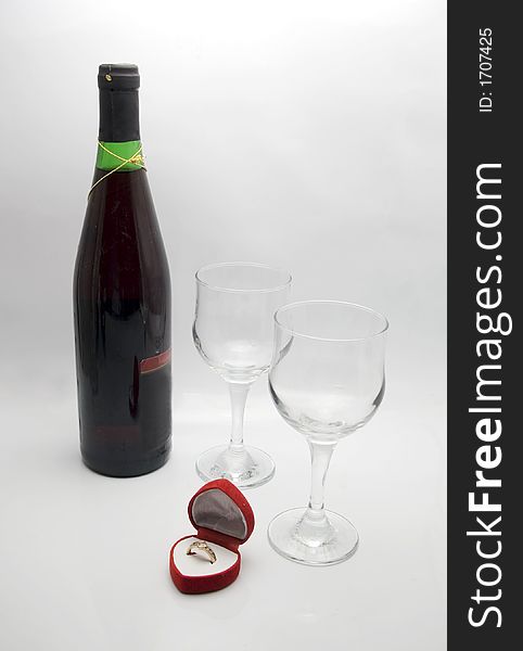 Wedding ring in a heart shaped box with glasses and a bottle of red wine. Wedding ring in a heart shaped box with glasses and a bottle of red wine