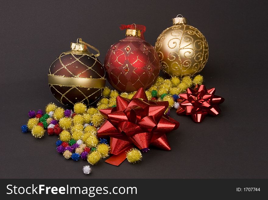 Detail of Christmas balls with bows and gold spike balls against a plain background.