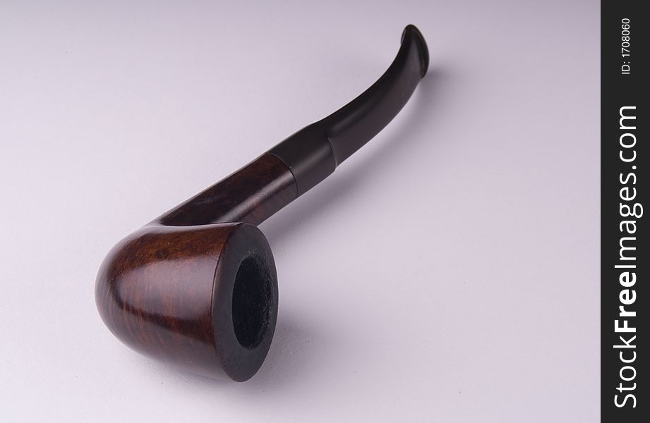 Tobacco pipe lying on its side on a plain white background