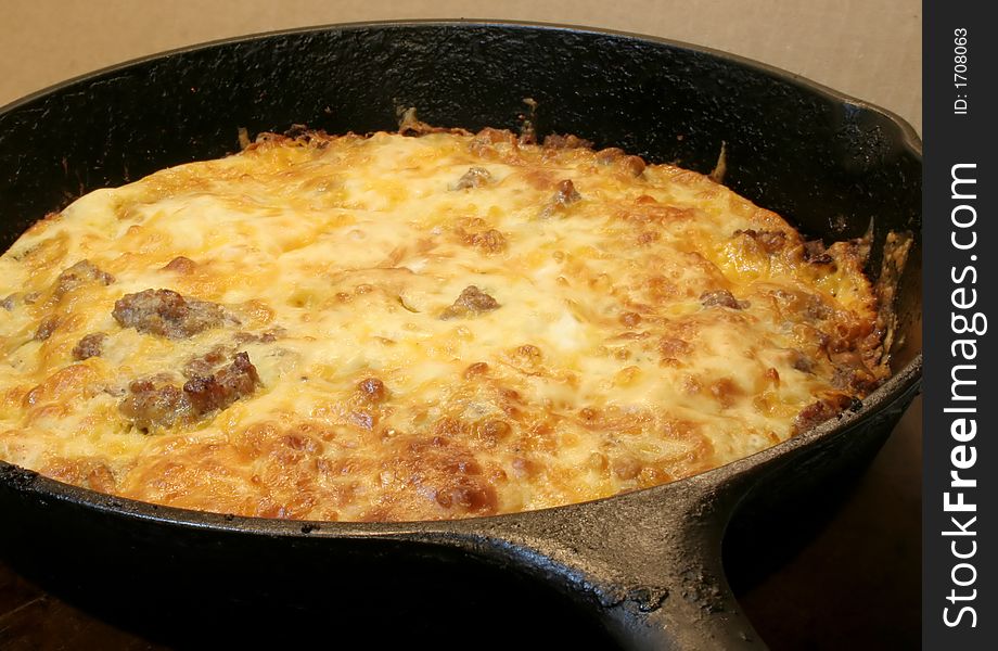 Pork sausage, biscuit mix, and chedder cheese casserole in a black cast iron skillet.