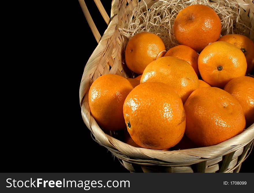 Clementines imported from Spain in a basket on a black background.  These are also knows as Satsumas and are grown in southern Louisiana.