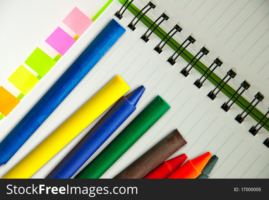 Isolated green notebook on white with colorful crayons. Isolated green notebook on white with colorful crayons