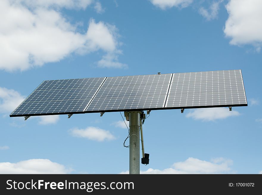 A modern photovoltaic solar panel array generates electricity with blue sky and clouds in the background. A modern photovoltaic solar panel array generates electricity with blue sky and clouds in the background.